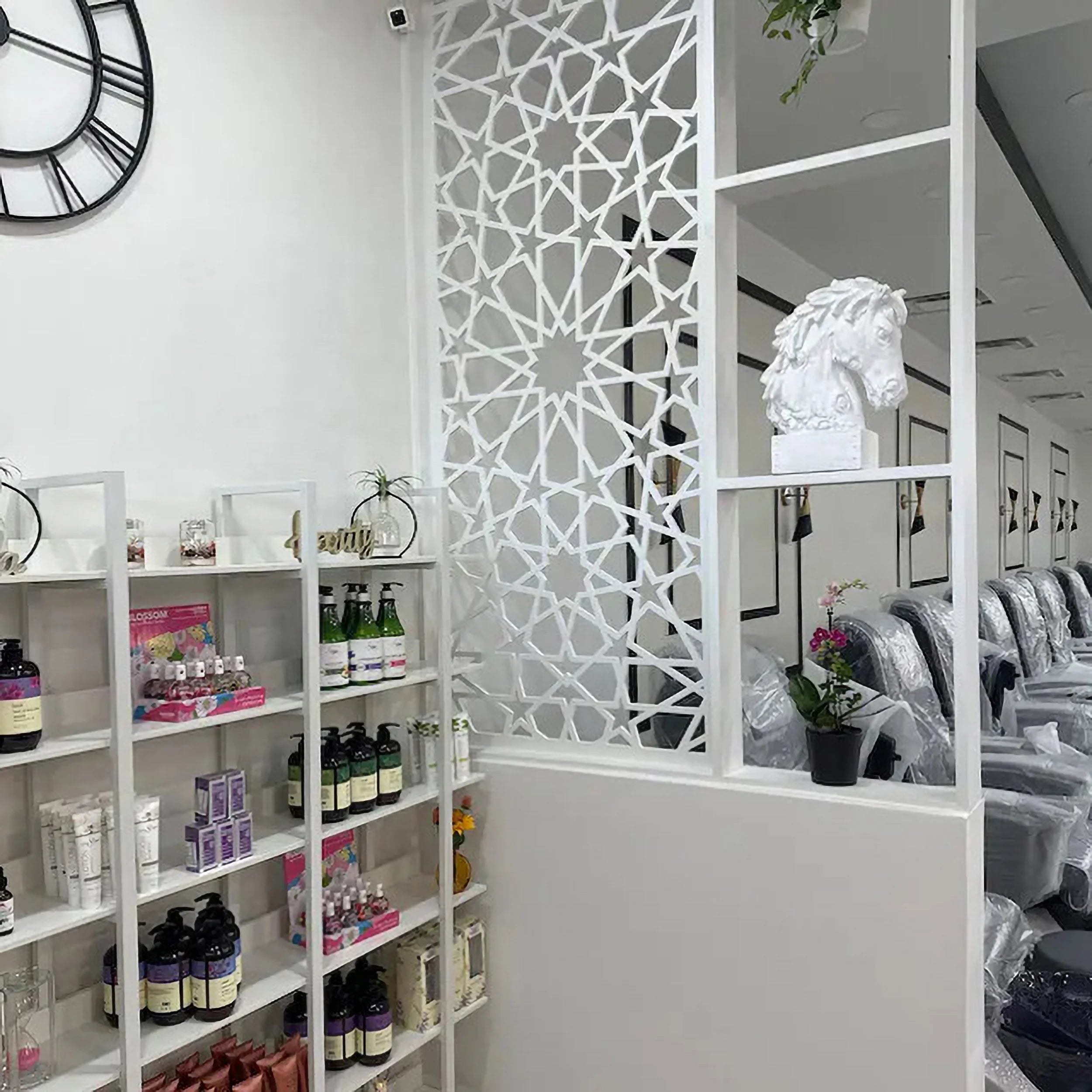 Salon interior with shelves displaying products, a decorative wall panel, and salon chairs.